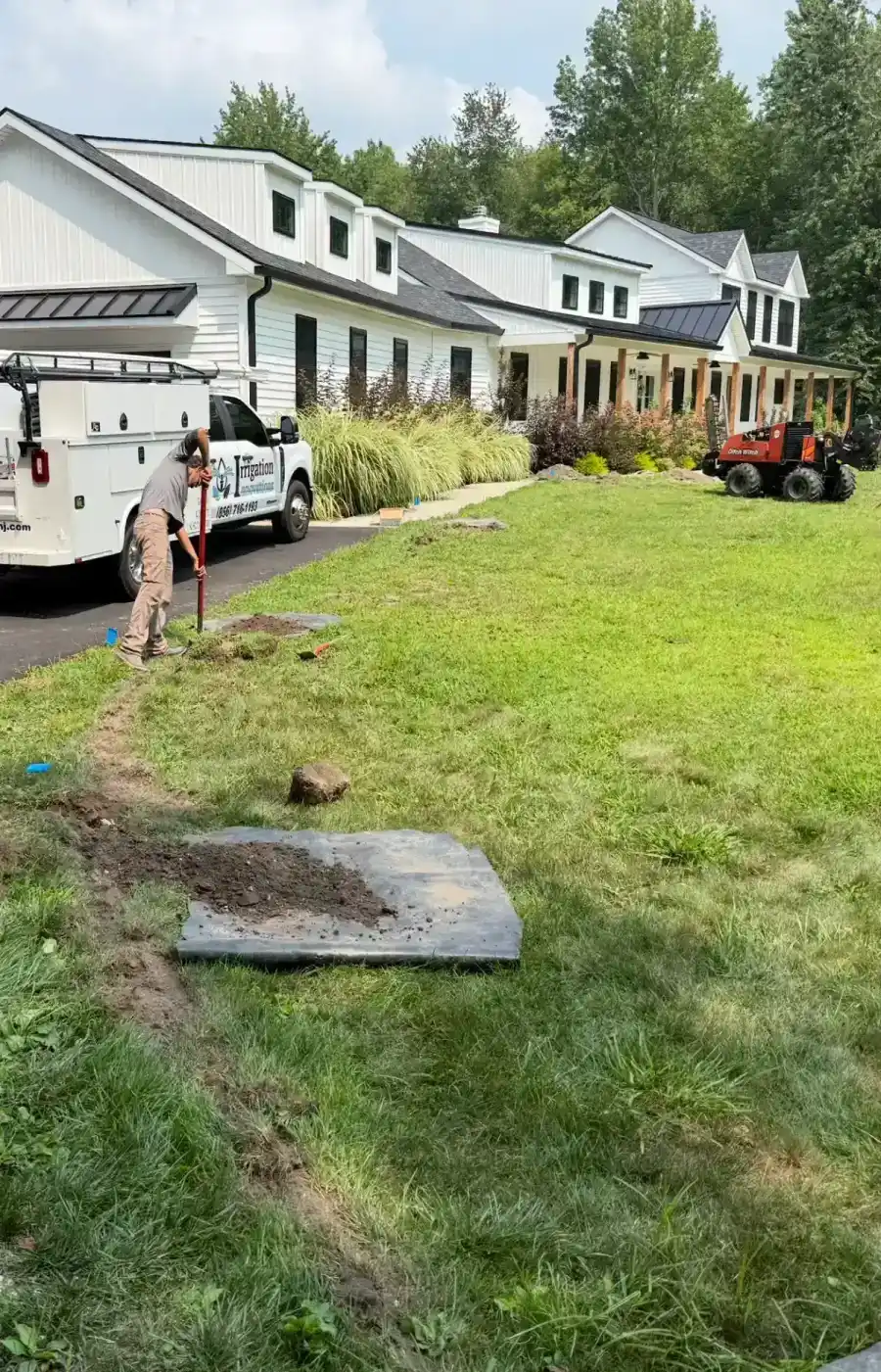 Irrigation Innovations crew installing a residential sprinkler system with trenching equipment
