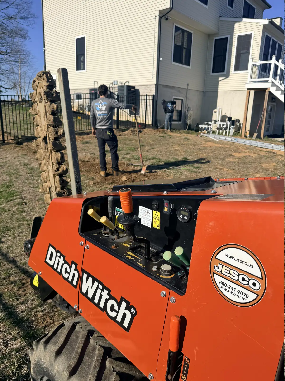 Professional irrigation system installation using Ditch Witch trencher in a South Jersey backyard