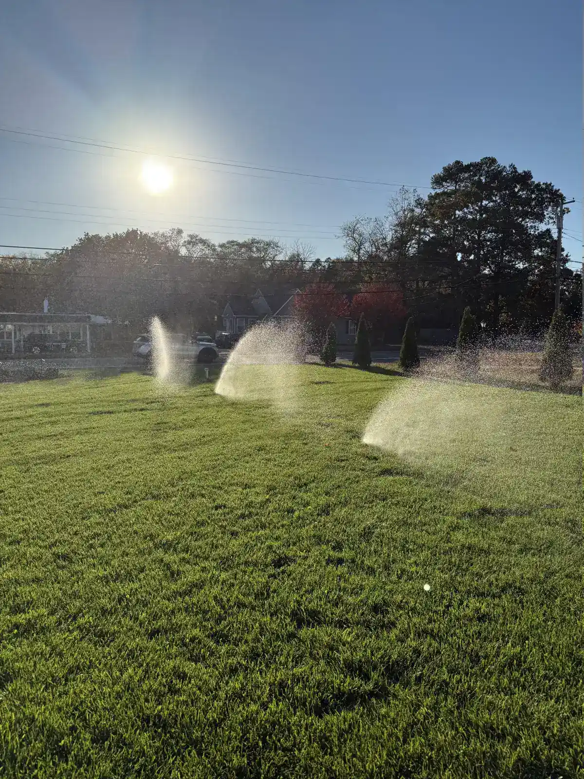 Residential lawn sprinkler system running at golden hour in South Jersey