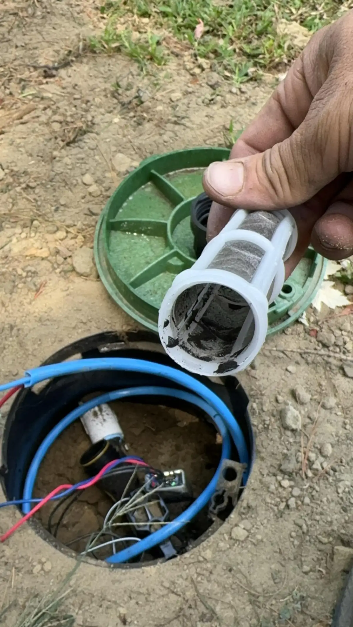Technician cleaning sprinkler filter during a maintenance service visit