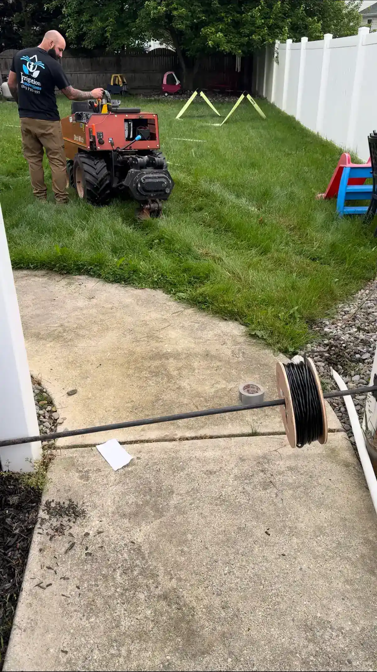 Irrigation Innovations crew member in branded shirt working with professional irrigation equipment